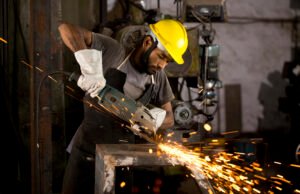 Mechanic using circular saw grinder tool at factory