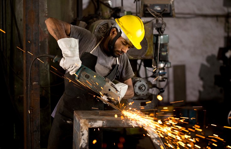 Mechanic using circular saw grinder tool at factory